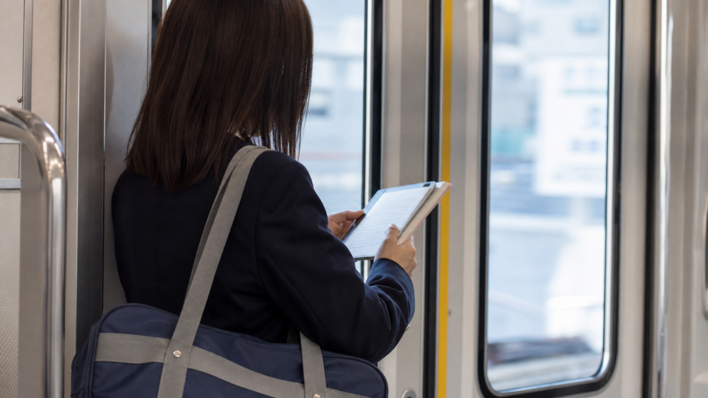 電車通学中に教材を見て勉強する受験生